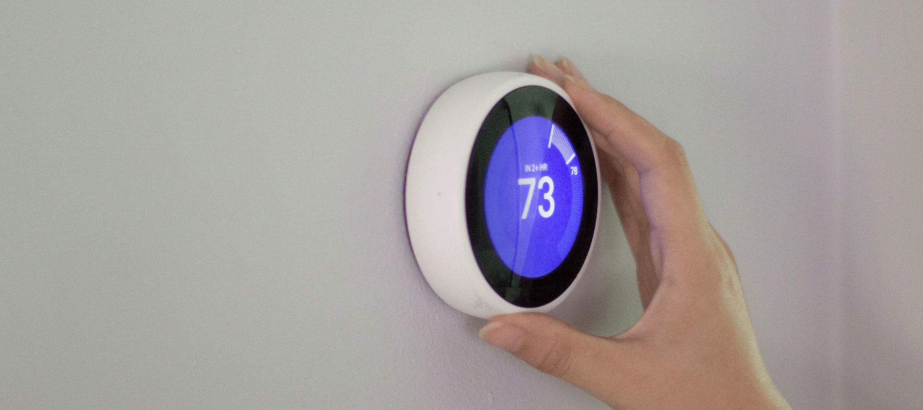 person adjusting a smart thermostat to the right temperature