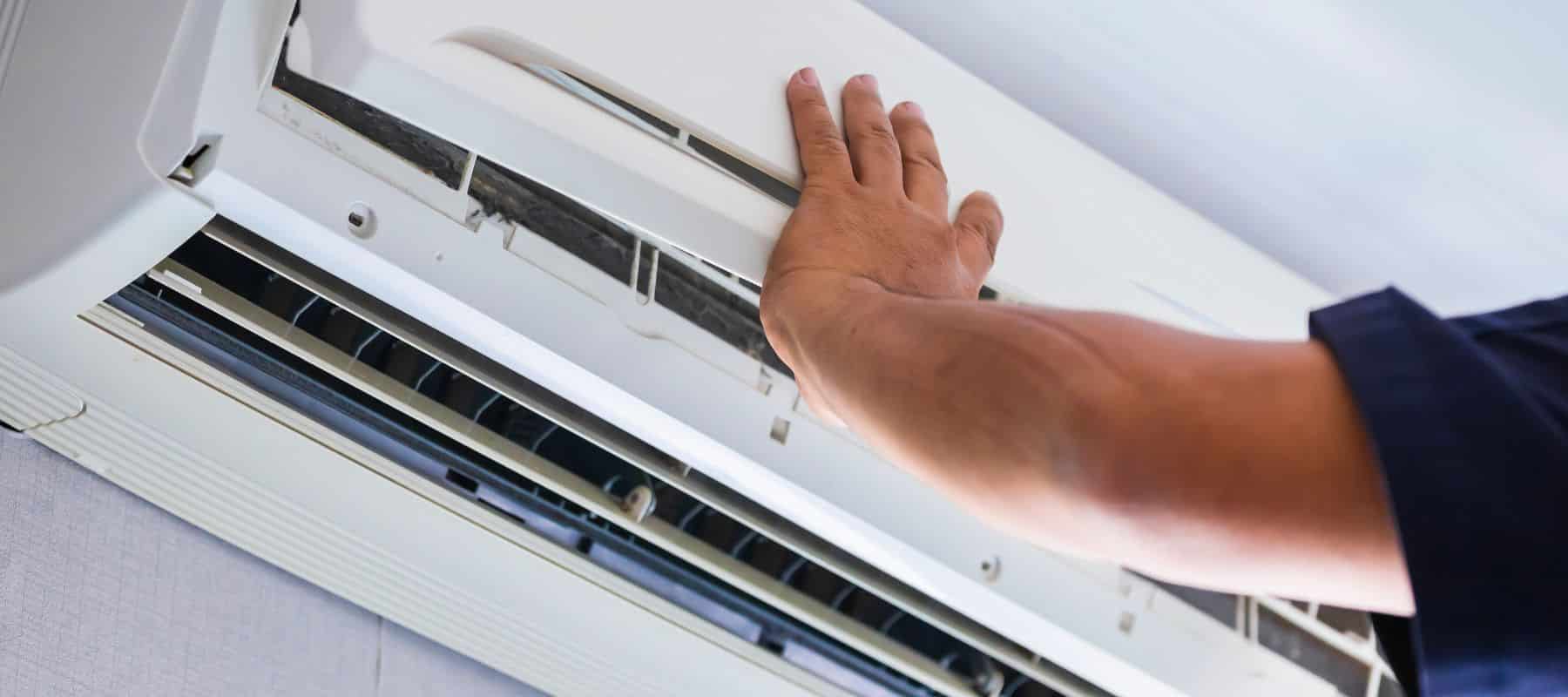 man pushing upward on a ductless ac unit