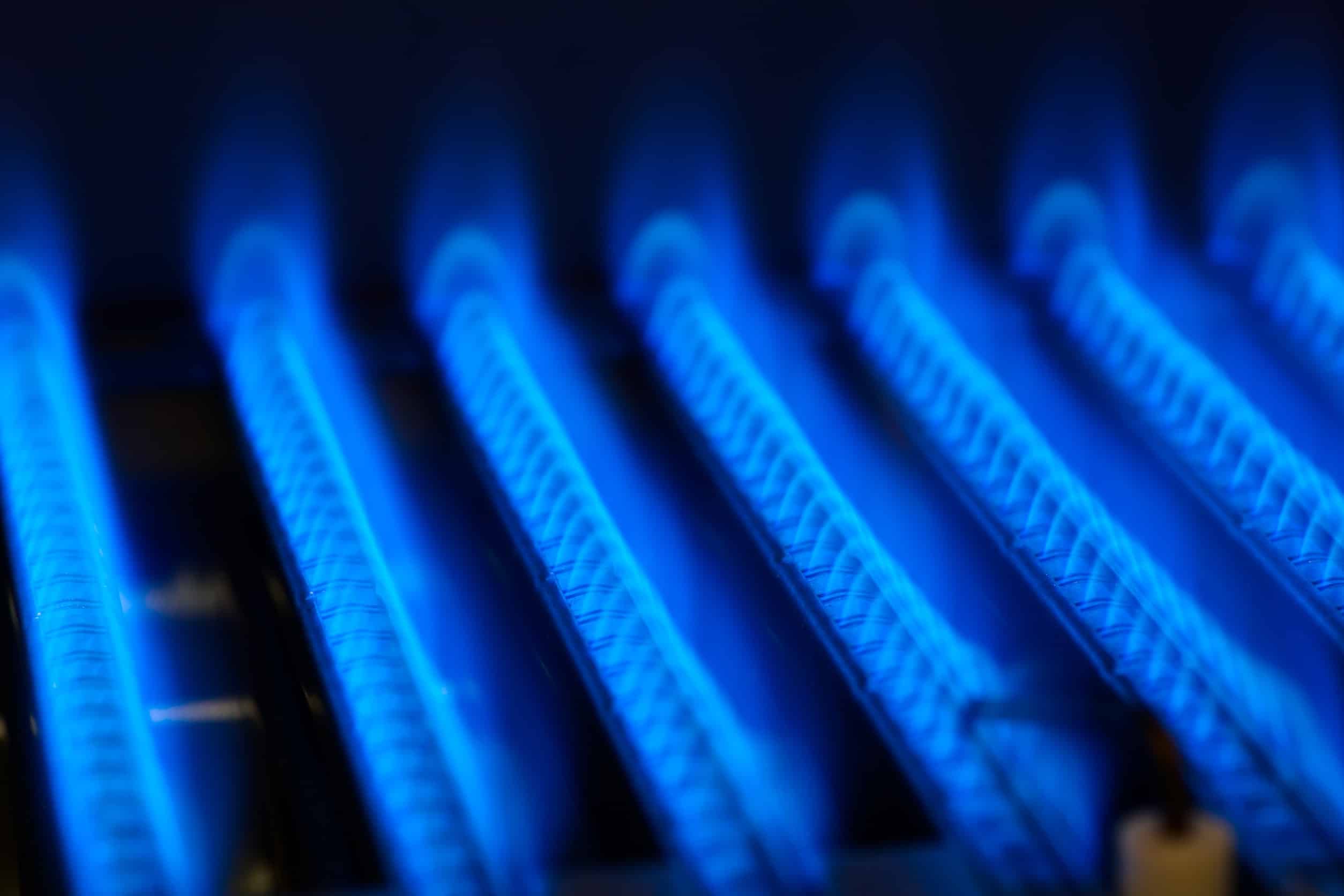six vertical angled rows of small blue flames inside a furnace