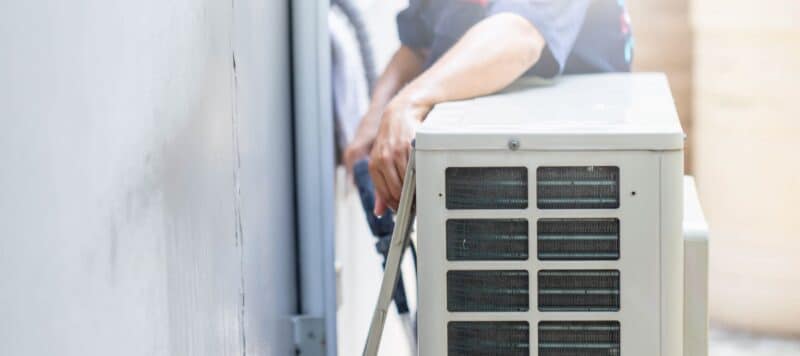 technician performing ac maintenance on a ductless outdoor unit