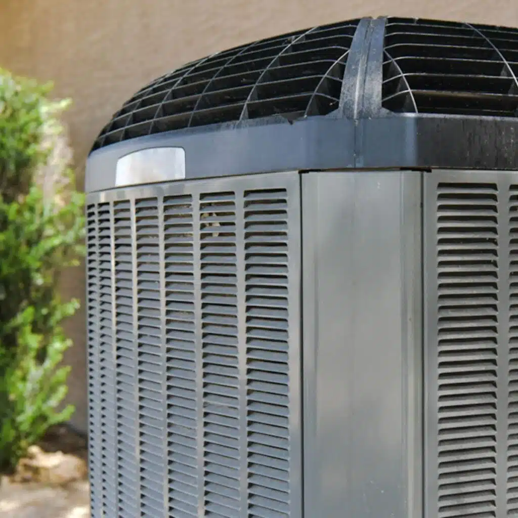 The top corner of an outdoor central air conditioning unit with a black grille.